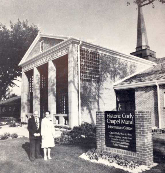 Photo of a couple next ti the chapel mural